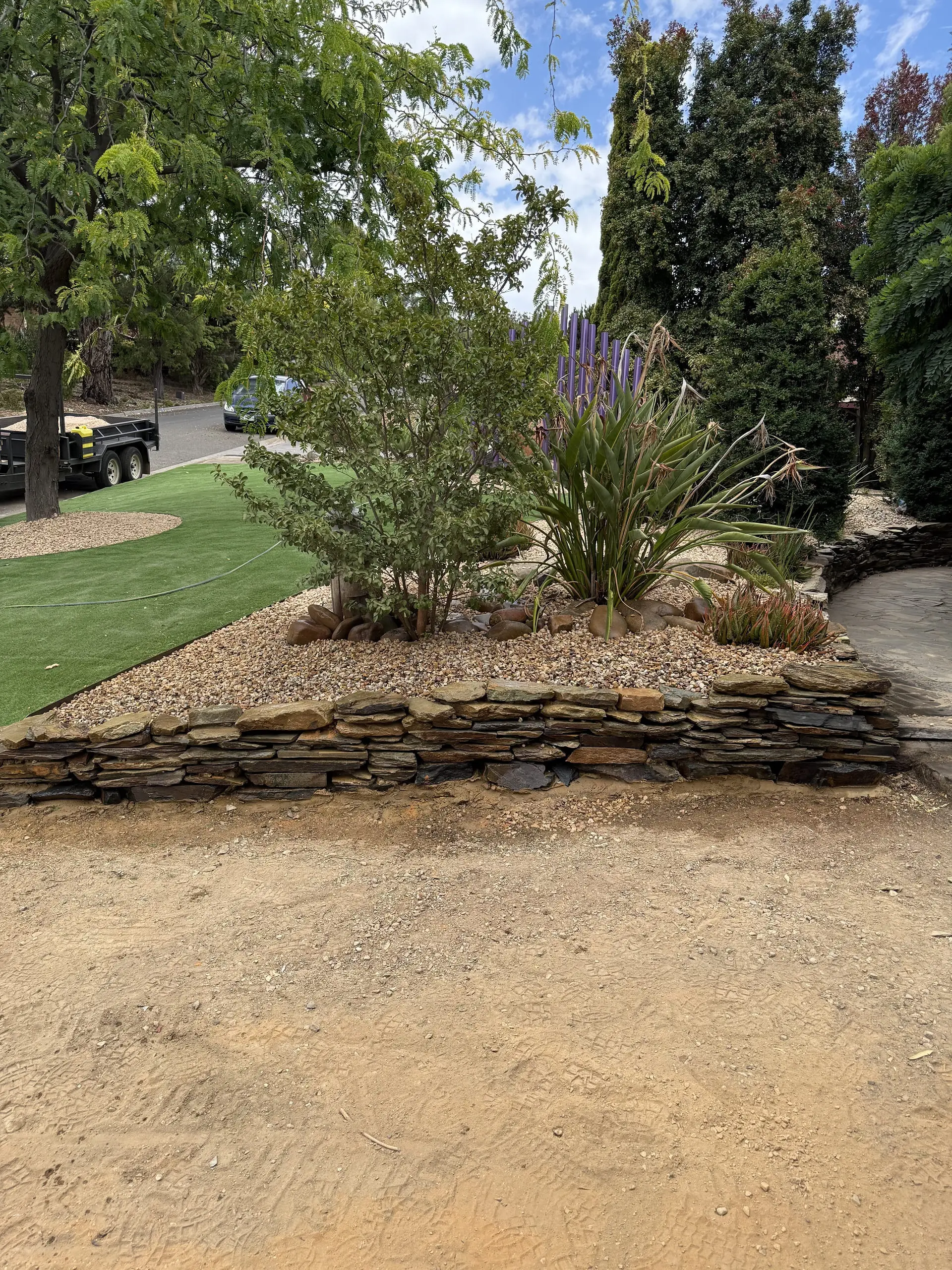 Raised dry stone retaining wall garden bed filled with native plants, ornamental grasses
